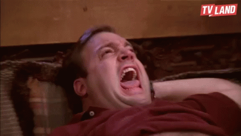 A Man Is Laying On A Couch With His Mouth Open And Laughing . GIF