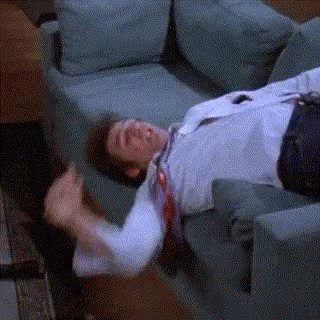 A Man Is Laying On A Couch With His Tie Hanging Off Of Him . GIF