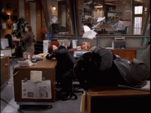 A Man Is Laying On A Desk In An Office GIF
