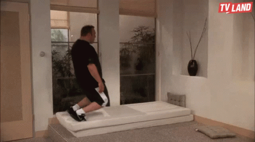 A Man Is Laying On A Mattress In A Room With A Tv Land Logo On The Wall GIF