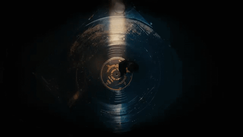 A Man Is Laying On A Record In The Dark . GIF