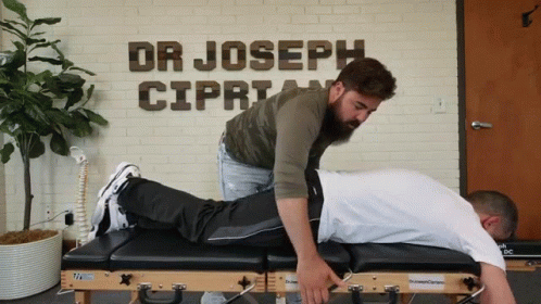 A Man Is Laying On A Table In Front Of A Wall That Says Dr Joseph Cipria GIF