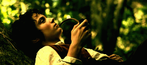 A Man Is Laying On A Tree Branch Holding A Pipe In His Hand GIF
