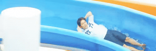 A Man Is Laying On A Water Slide Wearing A Shirt That Says ' I 'M Tired ' On It GIF