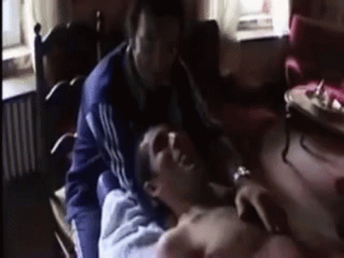 A Man Is Laying On Another Man 'S Chest In A Room . GIF