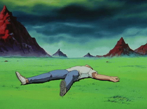 A Man Is Laying On His Back In A Grassy Field With Mountains In The Background GIF