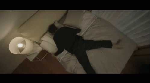 A Man Is Laying On His Back On A Bed With His Legs Crossed GIF