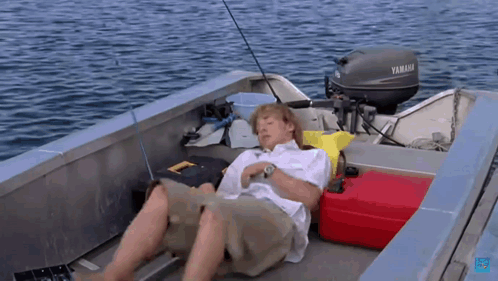 A Man Is Laying On The Deck Of A Boat With A Yamaha Motor GIF