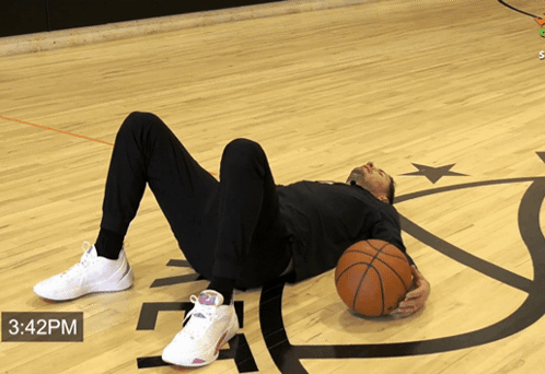 A Man Is Laying On The Floor Holding A Basketball With The Time Of 3:42 Pm GIF