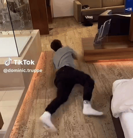 A Man Is Laying On The Floor In A Room With A Vans Couch GIF