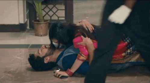 A Man Is Laying On The Floor With A Woman Holding Him . GIF