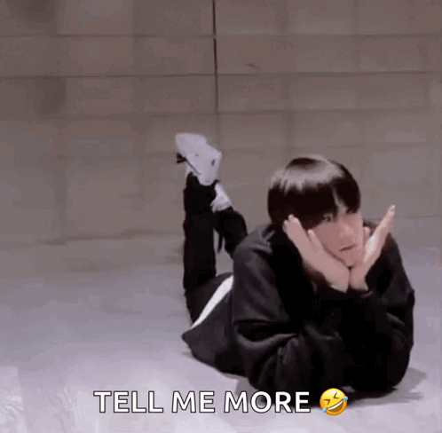 A Man Is Laying On The Floor With His Legs Crossed And The Words Tell Me More Below Him GIF