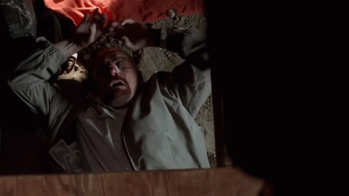 A Man Is Laying On The Floor With His Mouth Open And His Hands In The Air . GIF