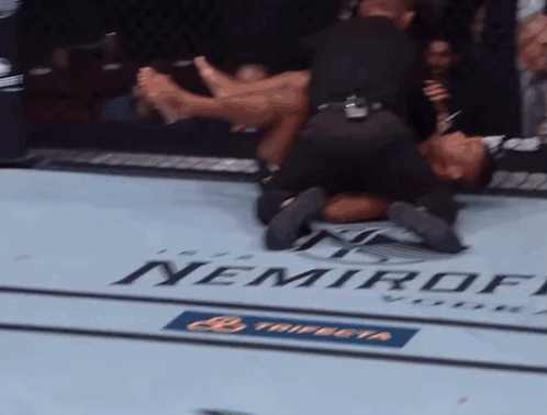 A Man Is Laying On The Ground In A Boxing Ring With A Nemiroff Logo On The Floor GIF