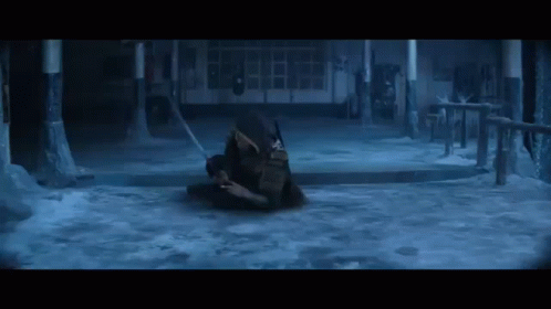 A Man Is Laying On The Ground In A Dark Room With A Sword In His Hand . GIF