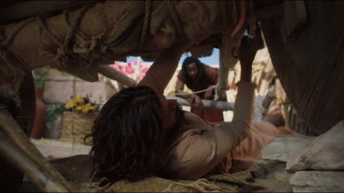 A Man Is Laying On The Ground While Another Man Stands Behind Him GIF
