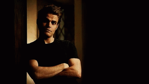 A Man Is Leaning Against A Wall With His Arms Crossed . GIF
