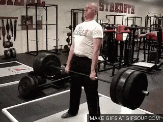 A Man Is Lifting A Barbell In A Gym That Has The Word Steeldata On The Wall GIF
