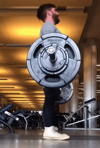 A Man Is Lifting A Barbell In A Gym That Says ' Smith ' On The Barbell GIF