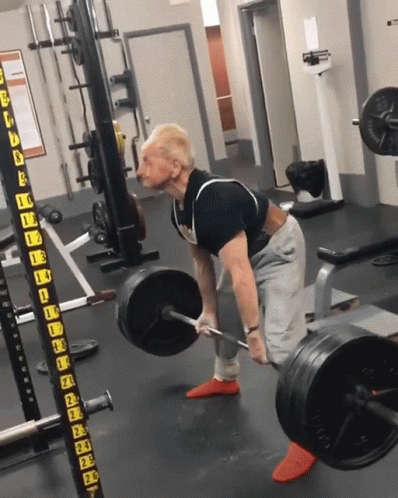 A Man Is Lifting A Barbell In A Gym With A Barbell Rack That Says ' A ' On It GIF