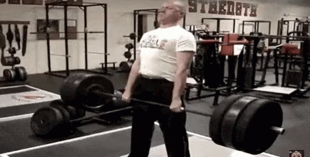 A Man Is Lifting A Barbell In A Gym With A Sign On The Wall That Says Strength . GIF