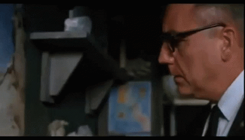 A Man Is Looking At A Painting On A Wall . GIF