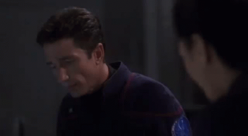 A Man Is Looking At A Woman In A Dark Room . GIF