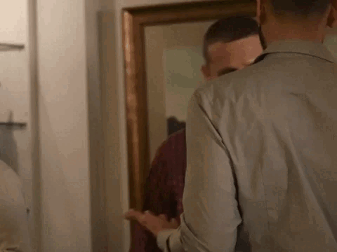 A Man Is Looking At Himself In The Mirror . GIF