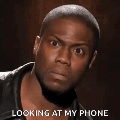 A Man Is Looking At His Phone While Wearing A Leather Jacket . GIF