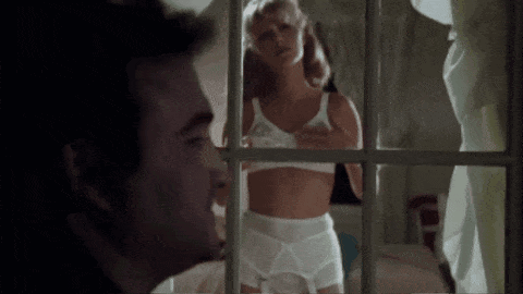 a man is looking out a window at a woman in lingerie .