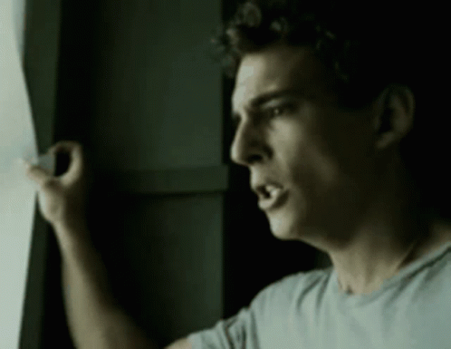 A Man Is Looking Out A Window With His Mouth Open GIF