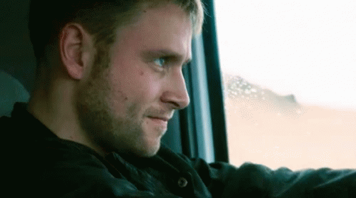 A Man Is Looking Out Of A Window While Driving A Car . GIF