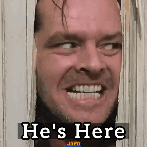 A Man Is Looking Through A Door With The Words He 'S Here Behind Him GIF