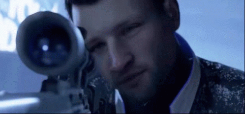 A Man Is Looking Through A Sniper Rifle With A Blue Background GIF