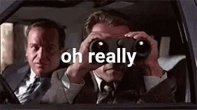 A Man Is Looking Through Binoculars In A Car While Another Man Looks Out The Window . GIF