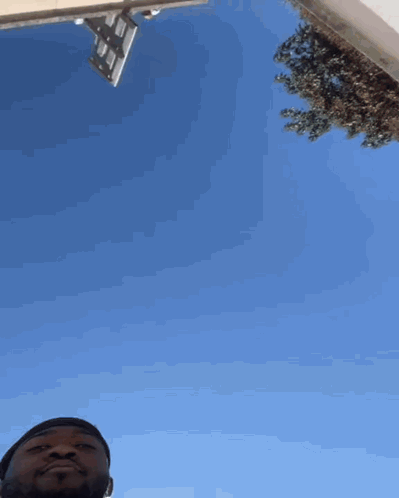 A Man Is Looking Up At A Blue Sky GIF