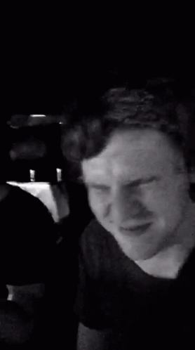 A Man Is Making A Funny Face In A Black And White Photo While Sitting In A Car . GIF