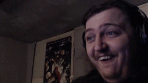 A Man Is Making A Funny Face In A Dark Room . GIF