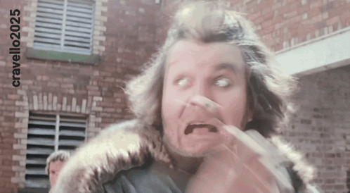 A Man Is Making A Funny Face In Front Of A Brick Building With The Hashtag Cravello2025 GIF