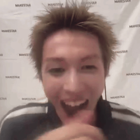 A Man Is Making A Funny Face In Front Of A Makestar Banner . GIF