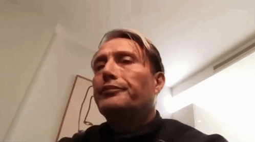 A Man Is Making A Funny Face While Sitting In A Chair In A Room . GIF