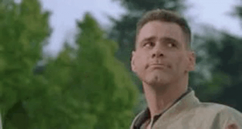 A Man Is Making A Funny Face While Standing In Front Of A Tree . GIF