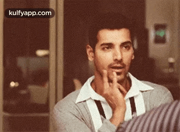 A Man Is Making A Funny Face While Talking To Another Man . GIF