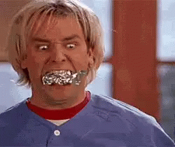 A Man Is Making A Funny Face With A Piece Of Tinfoil In His Mouth . GIF