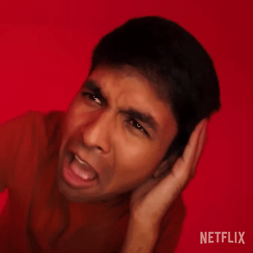 A Man Is Making A Funny Face With His Hands Behind His Ears . GIF