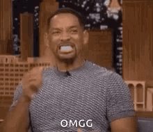 A Man Is Making A Funny Face With His Mouth Open And A Fist In His Hand . GIF