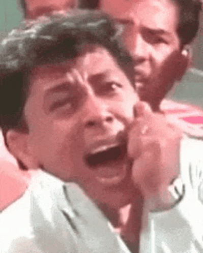 A Man Is Making A Funny Face With His Mouth Open In A Crowd . GIF