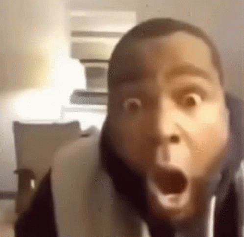 A Man Is Making A Funny Face With His Mouth Open While Sitting On A Couch . GIF