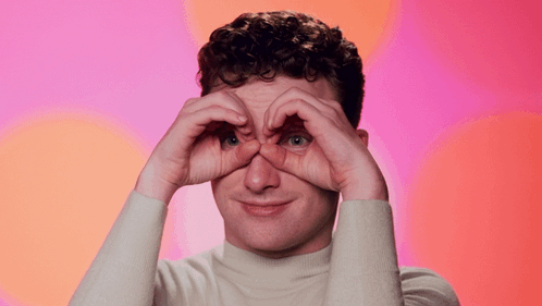 a man is making a heart shape with his hands and the words blink blink are above him