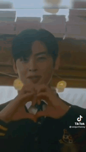 A Man Is Making A Heart Shape With His Hands In A Restaurant . GIF
